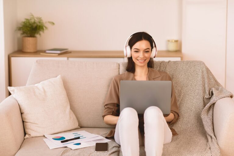 Girl listening to music online in headphone sitting on sofa